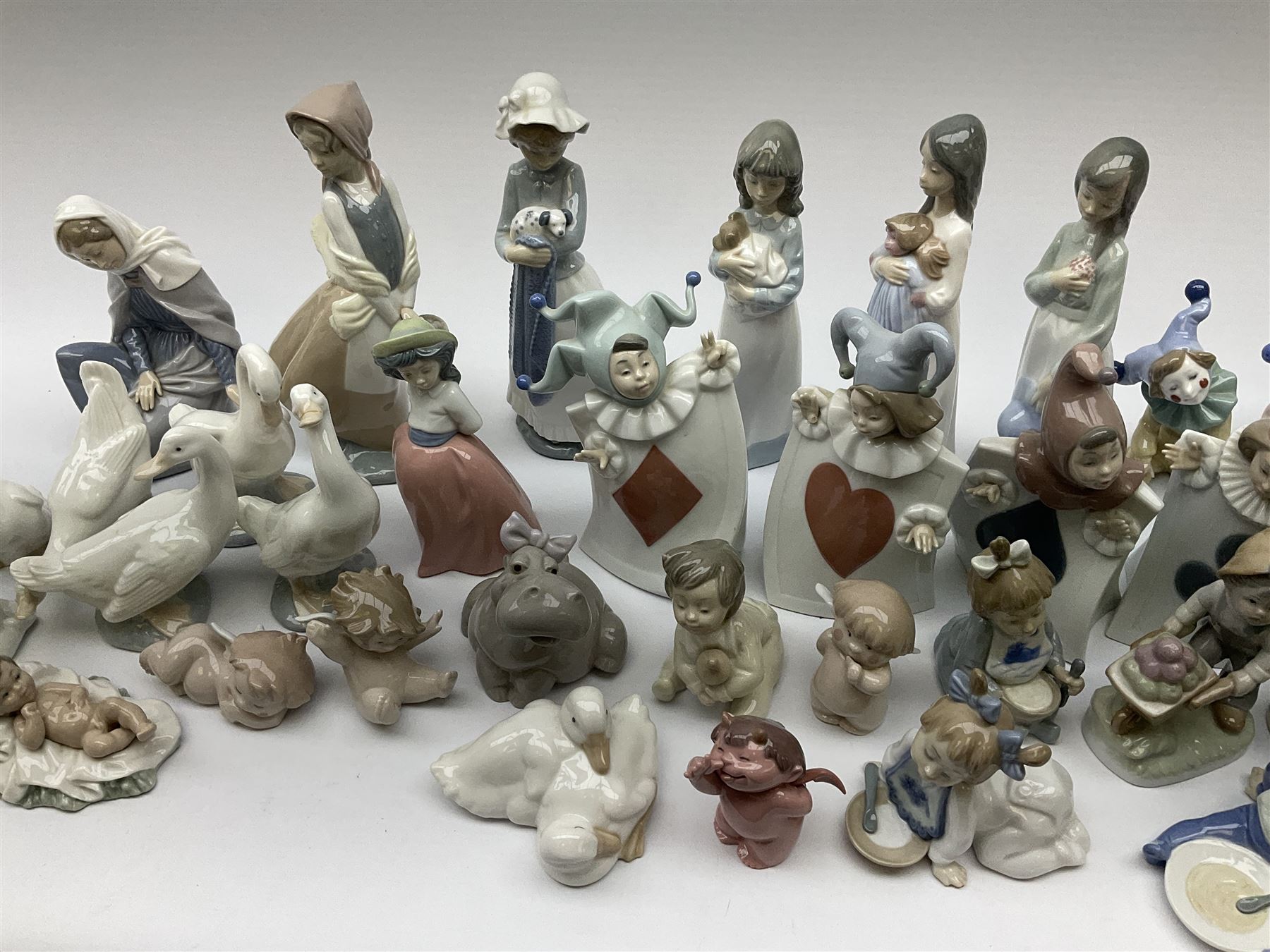 Collection of Nao figures, including four playing card jesters, two clowns, Virgin Mary and baby Jesus , five geese etc. 