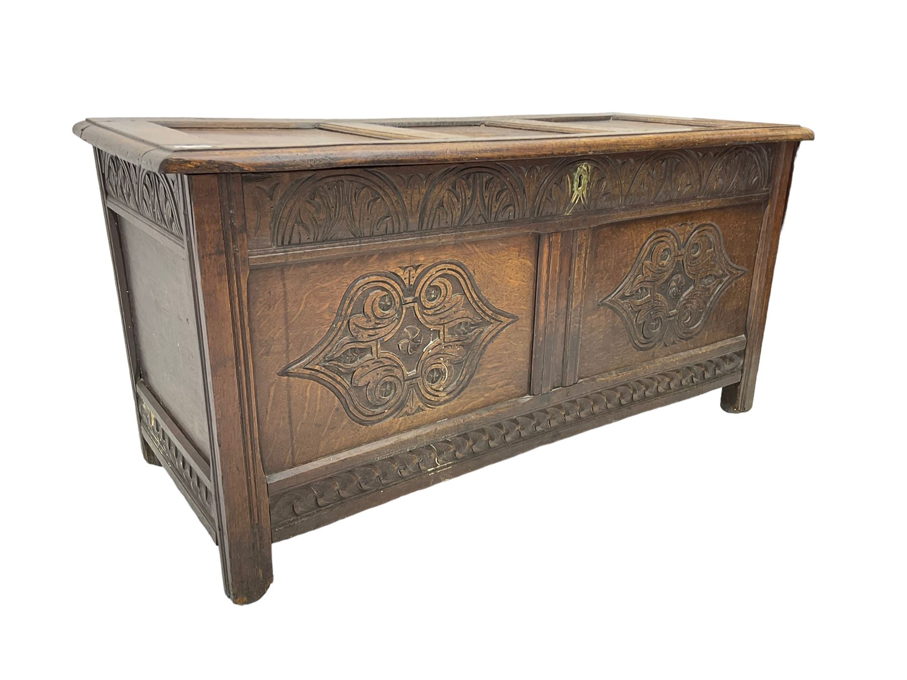 18th century oak blanket chest or coffer, rectangular hinged top with three panels and moulded edge, frieze carved with lunette and acanthus leaf decoration, two front panels carved with scrolling motif, raised on stile supports
