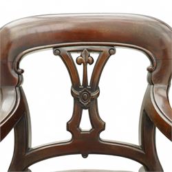 Victorian mahogany library elbow chair, arched cresting rail over shaped and pierced splat carved with cartouche, upholstered arms and seat in brown leather with studded bands, turned and lobe carved front supports on brass and ceramic castors 