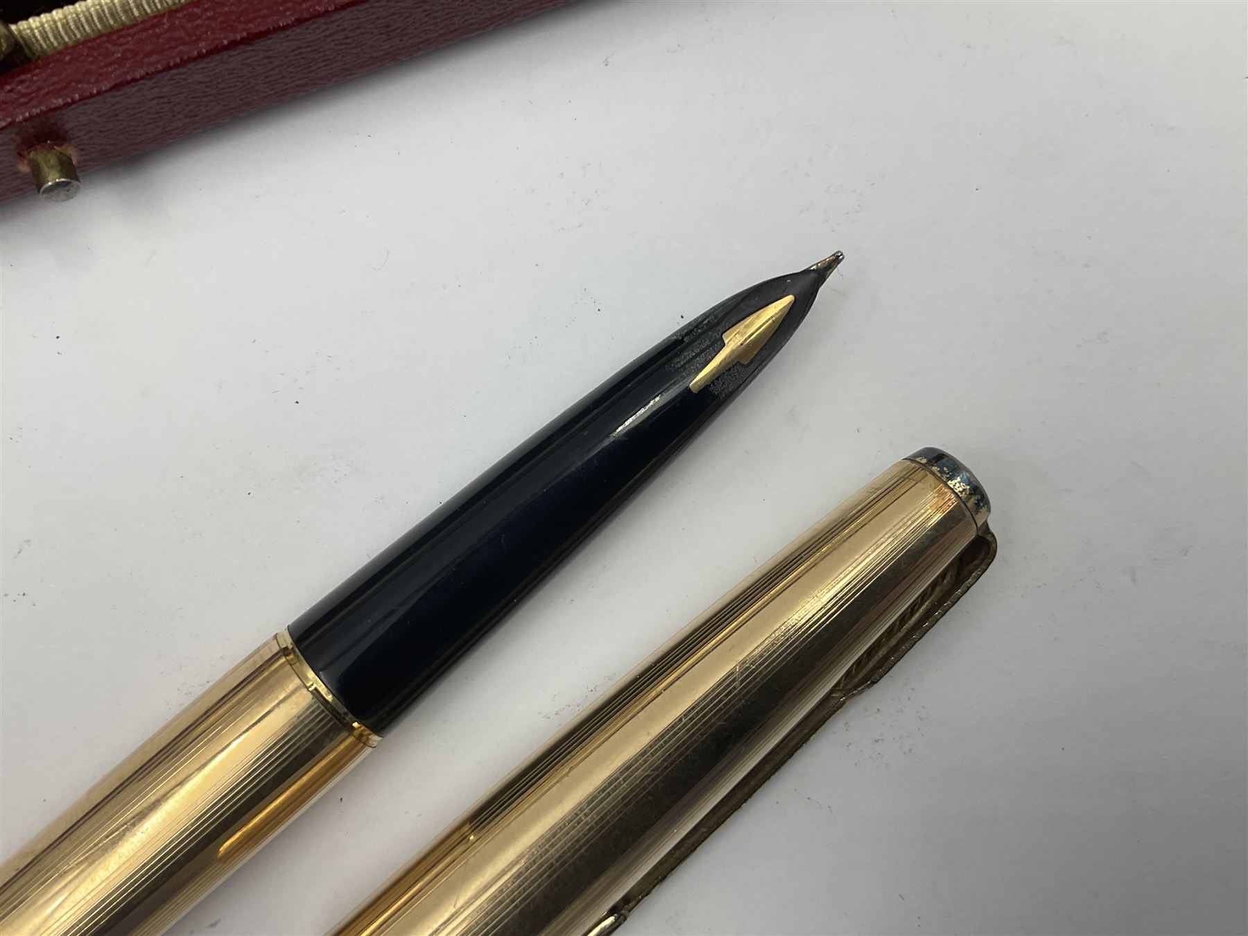 Three rolled gold Parker fountain pens, comprising an example with a gold nib marked 14K 585 and barrel with a shell stamp, a Parker 61 fountain pen with inset gold arrow to the nib, and another similar, all with striated decoration and arrow clips to the caps, L13cm, one with box
