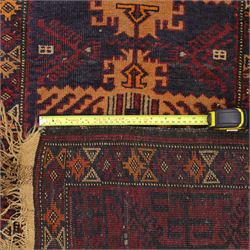 Baluch hand-knotted rug, deep red and indigo field decorated with a vertical arrangement of stylized geometric medallions within multiple narrow borders, 95x163cm, and Tekke Turkman rug, madder red field decorated with repeating rows of octagonal guls, framed by multiple geometric borders 84x129cm, (2)