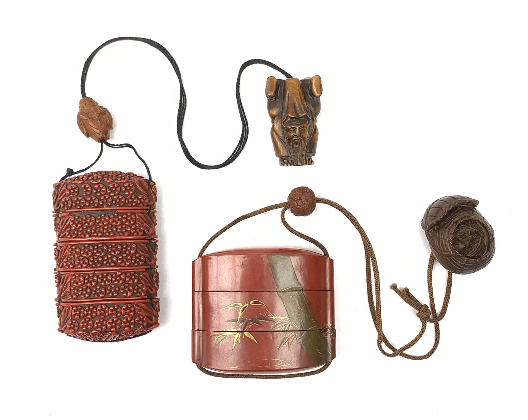 A Japanese cinnabar lacquer inro, of five sectional form, the whole with carved foliate detail, with wooden ojime, and carved hardwood Netsuke modelled as one of the Lucky Gods, Fukurokuju standing upon his hands, inro H8.5cm, together with a Japanese lacquer inro, of three sectional form, detailed with a tiger and bamboo branches, with ojime, and wooden netsuke modelled as a basket with animals within, inro H6cm.