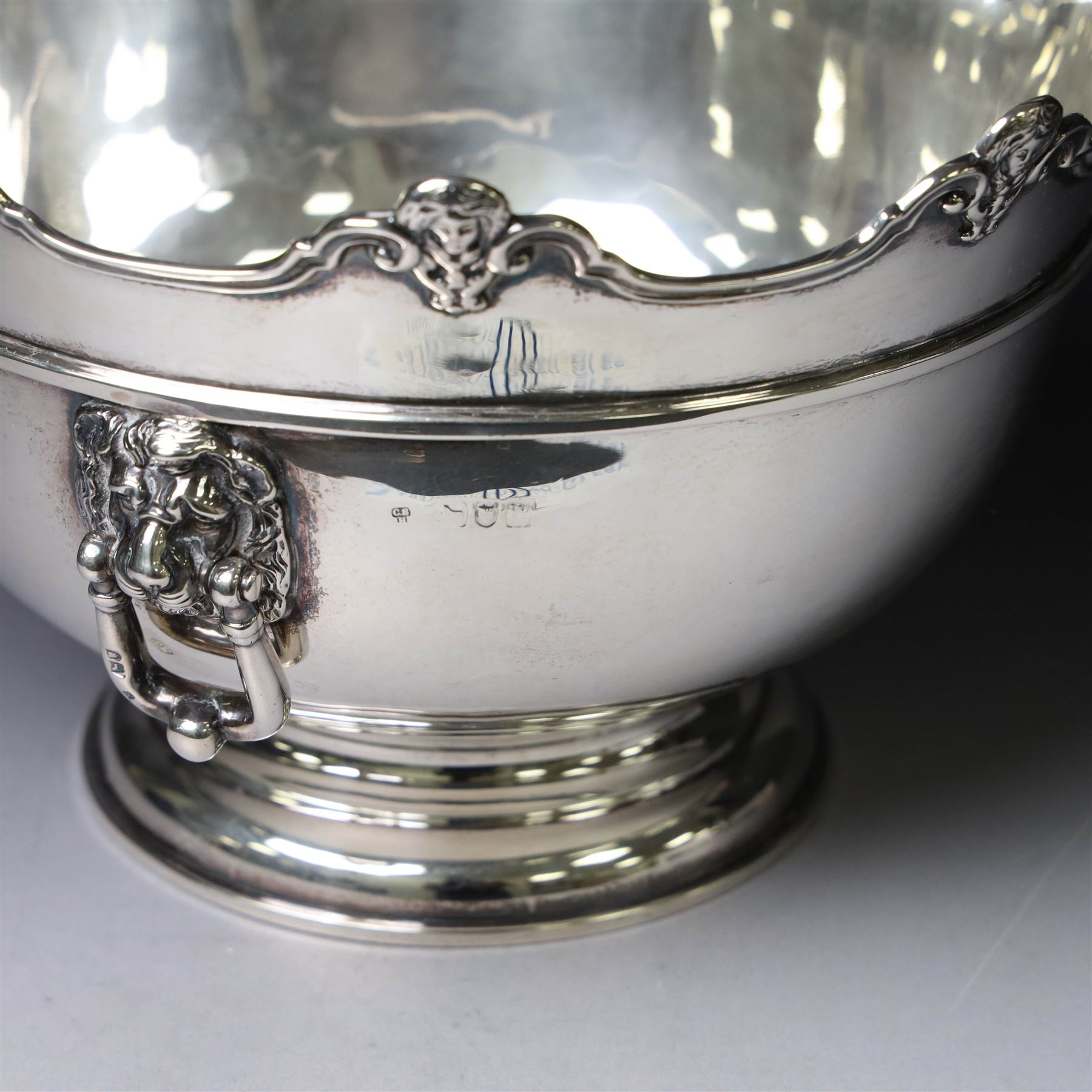 Edwardian silver Monteith punch bowl, the scalloped rim with strapwork and figural decoration, with two lion mask mounted ring handles, upon a circular stepped foot, hallmarked London 1903, maker's mark worn and indistinct, H15cm, D23cm