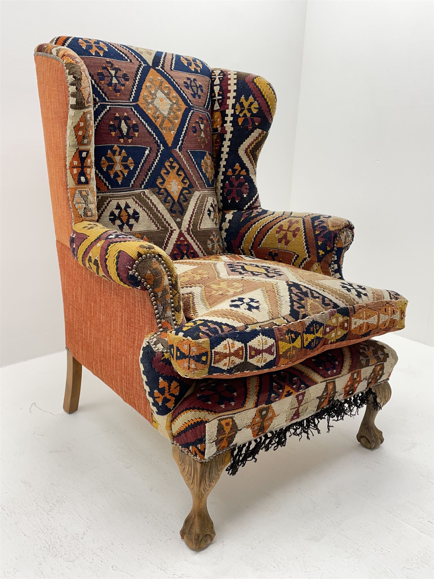 Late 20th century beech framed wingback armchair, sprung seat and back upholstered in kilim cover, acanthus carved cabriole supports with ball and claw feet