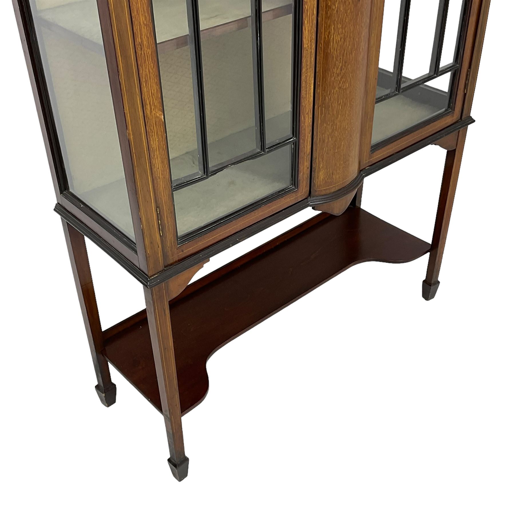 Edwardian inlaid mahogany display cabinet, enclosed by two astragal glazed doors, bowed centre inlaid with ribbon and trailing bellflowers, on square tapering supports with spade feet united by undertier 