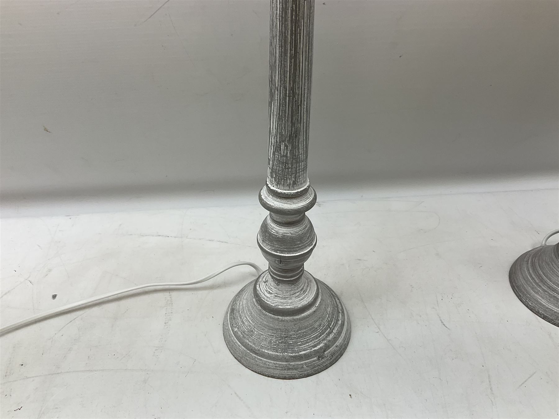 Pair of composite grey washed table lamps with a slender column upon a circular foot with natural linen shades