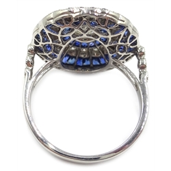  Sapphire and diamond circular platinum (tested) ring, the central diamond surrounded by calibre cut sapphires, halo of diamonds and outer calibre cut sapphires  