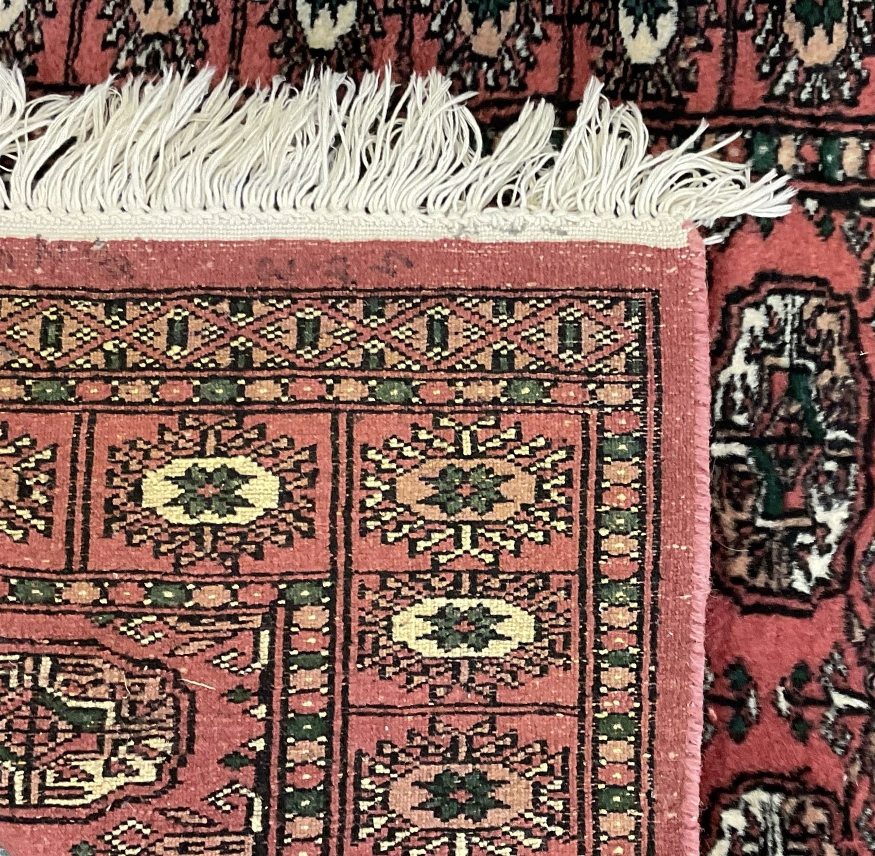 Small peach ground Bokhara rug, decorated with two rows of Gul motifs 