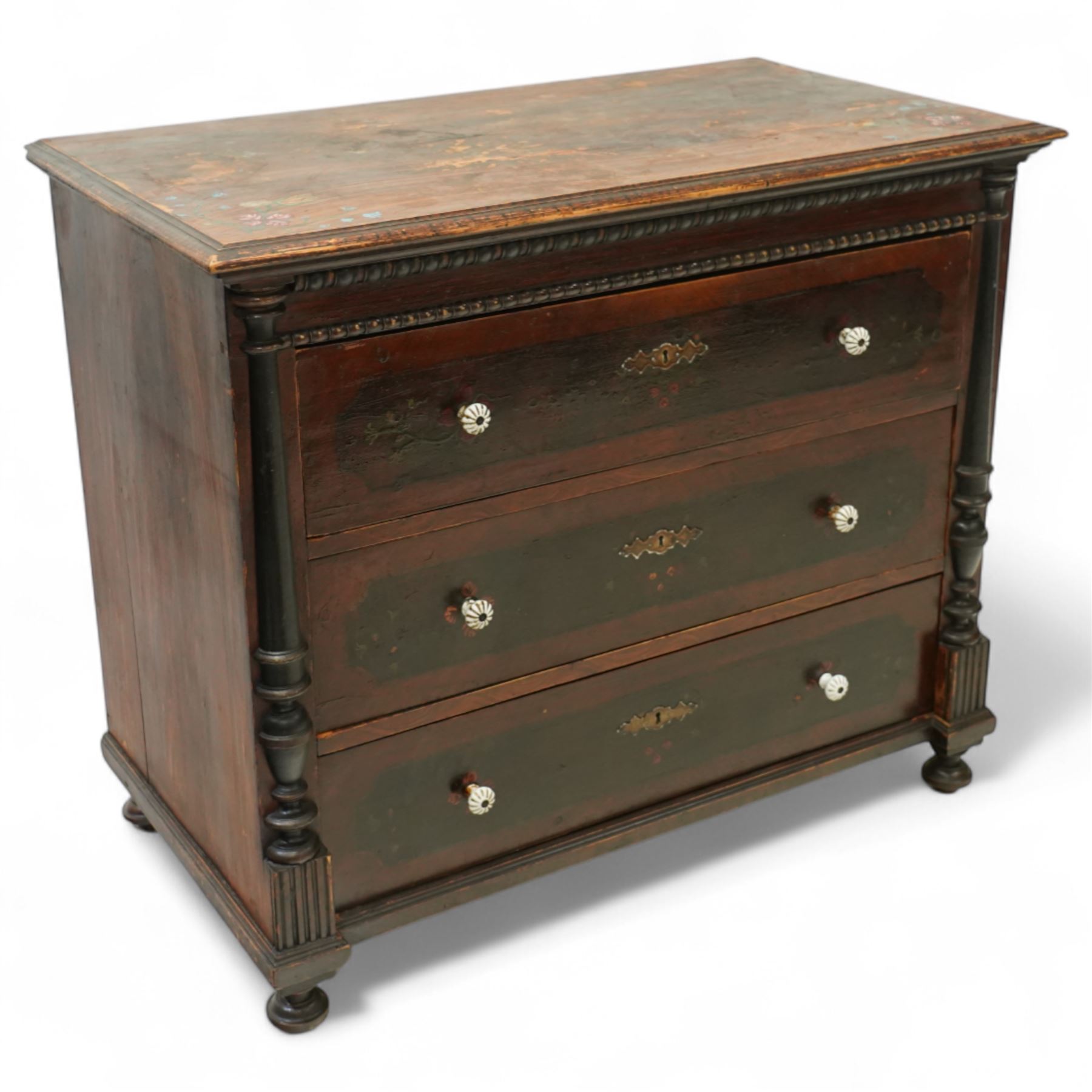 19th century painted pine chest of drawers, the rectangular top with moulded edge and painted floral decoration, above three drawers with later ceramic handles, with half turned column and reeded pilasters, upon turned compressed bun feet  