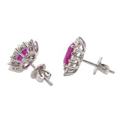 Pair of 18ct white gold ruby and diamond cluster earrings, each stud set with a single oval cut ruby and twelve round brilliant cut diamonds, stamped 750, total ruby weight approx 2.30 carat, total diamond weight approx 0.50 carat