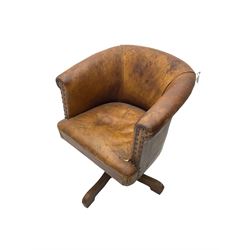 Early 20th century tub swivel armchair, upholstered in tan leather with studwork