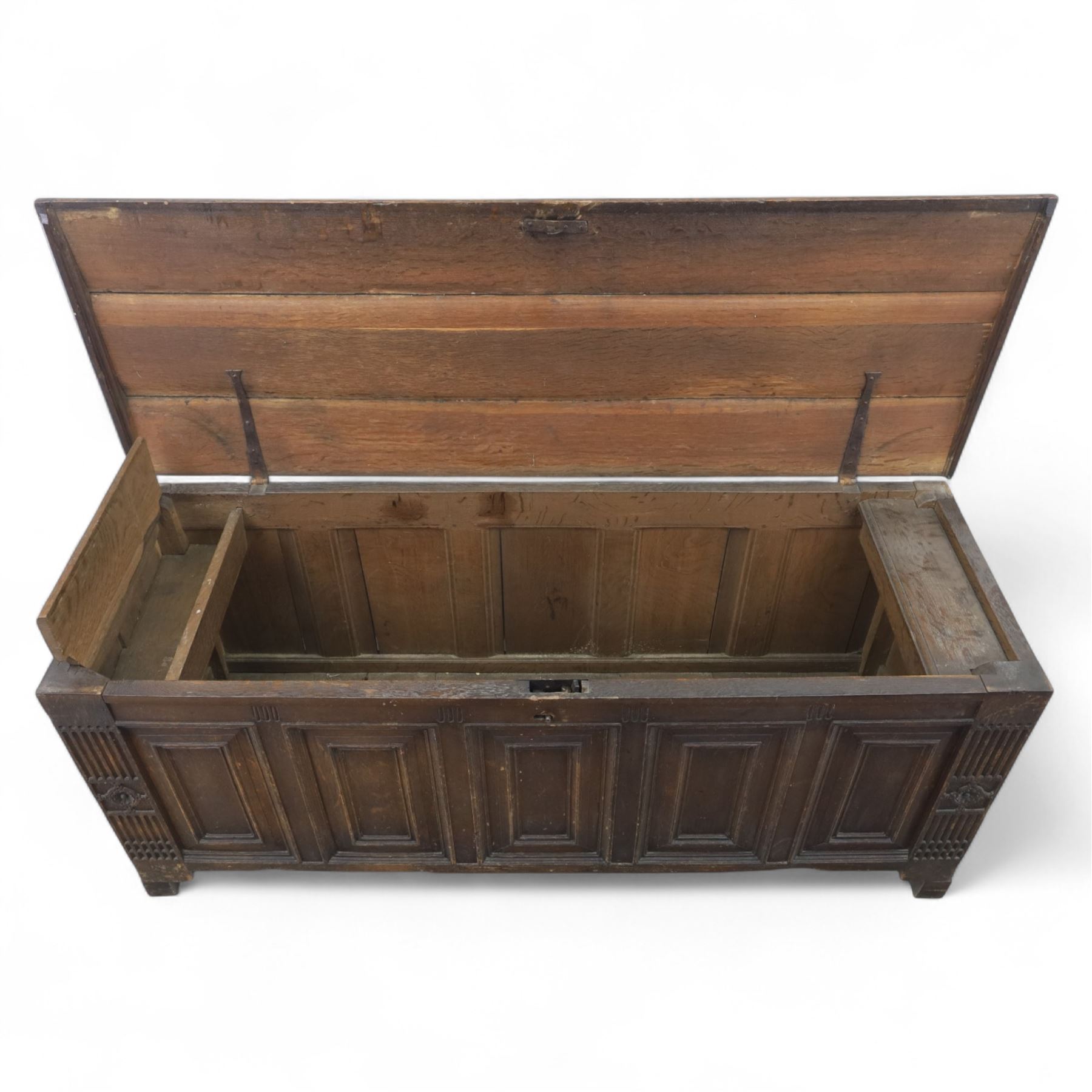 18th century oak five panel chest, with planked top with chamfered edges, hinged top enclosing two candle boxes, five fielded panels flanked by foliate carvings, raised on stile supports