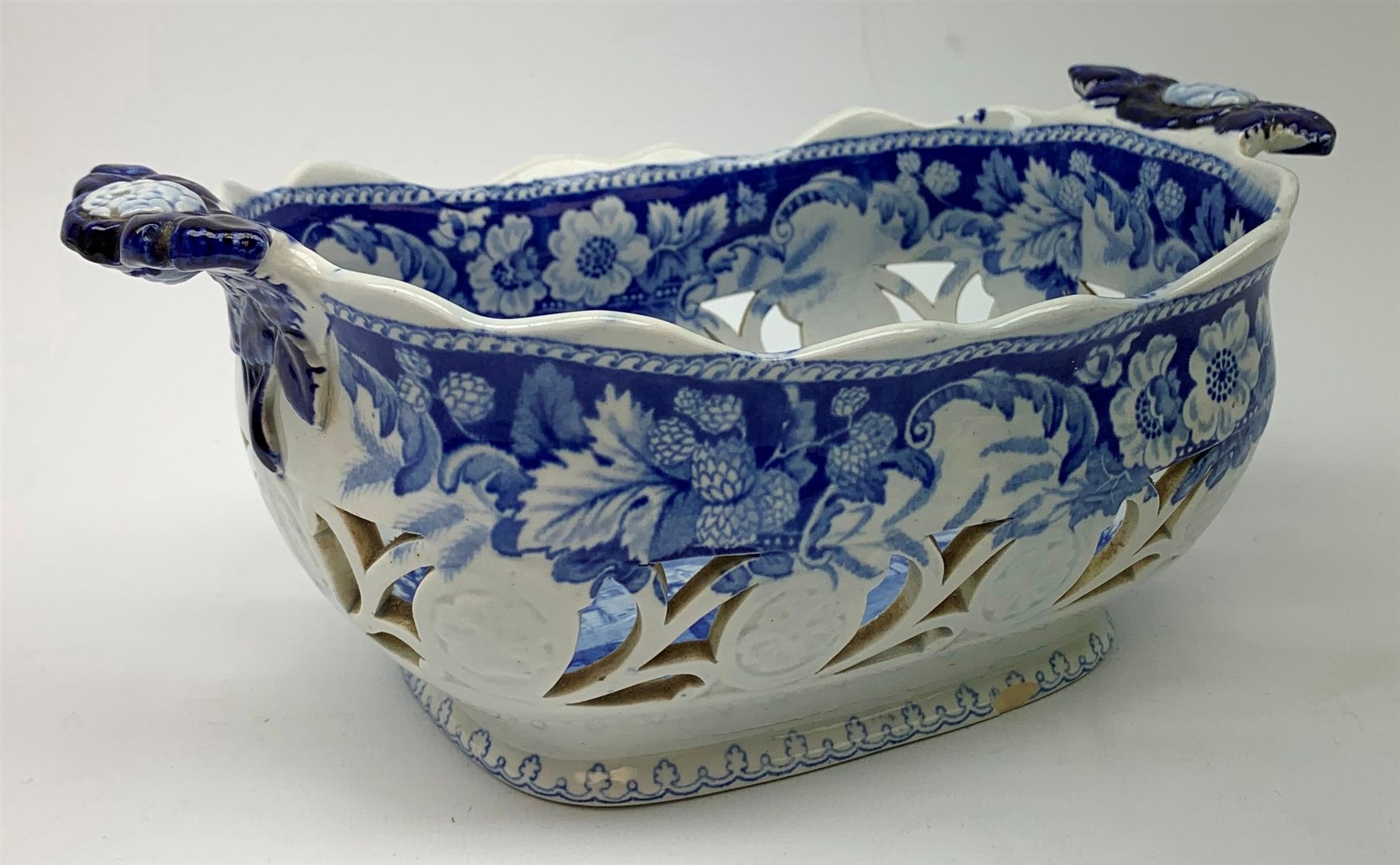 Mid 19th century blue and white transfer printed pearlware reticulated chestnut basket, of oval form with twin handles, decorated to the interior with figures before a classical temple within a garden setting, including handles W26cm, together with a mid 19th century blue and white transfer printed pearlware stand with reticulated edge, decorated with a Willow Pattern, L25cm, and a John and William Ridgeway blue and white transfer printed twin handled pierced basket, decorated with a pastoral scene containing figures at work, with printed mark beneath, including handles L25cm