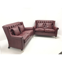 Pair Duresta two seat high back sofas upholstered in deep buttoned maroon leather, ebonised supports on chrome castors, W150cm