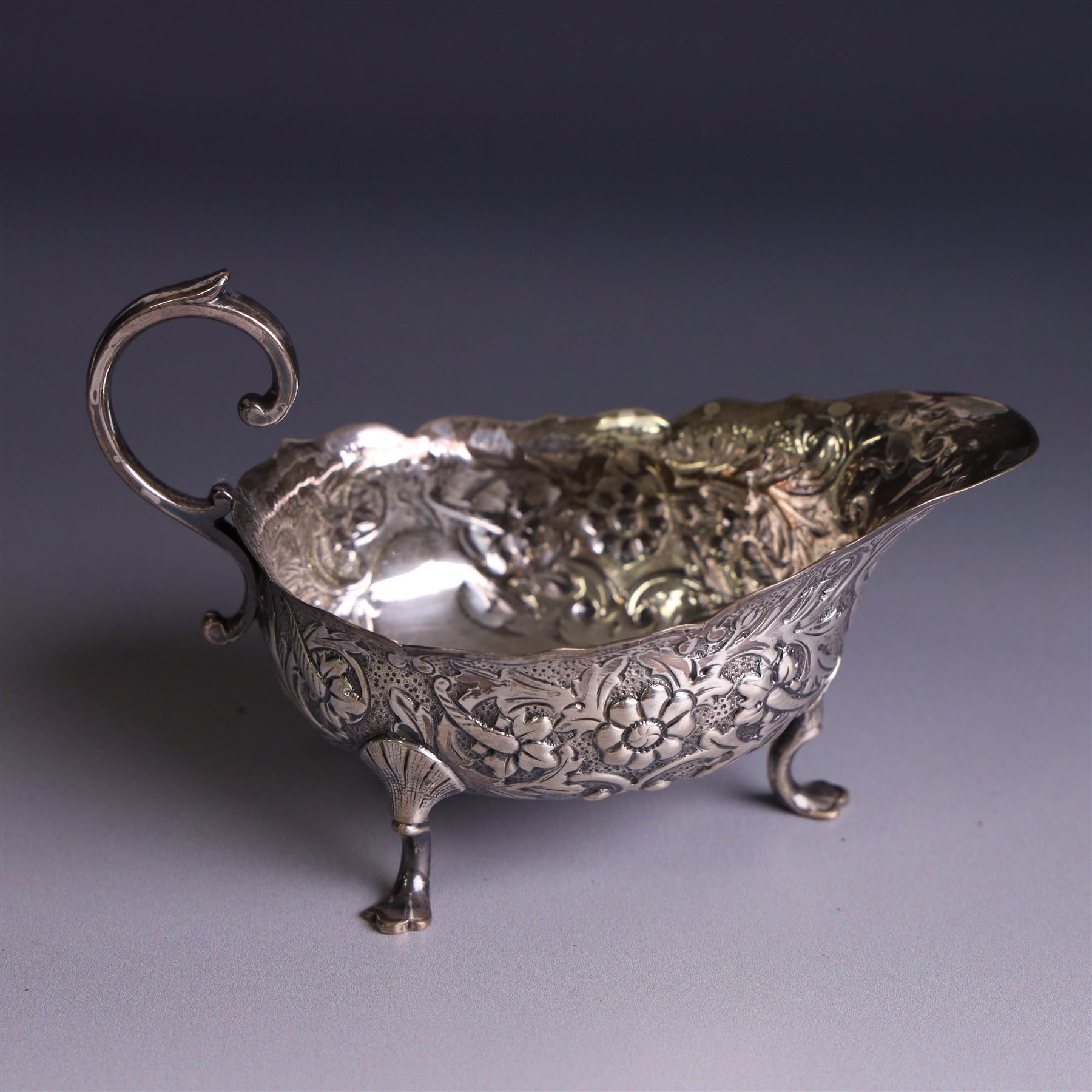 Victorian silver sauceboat, of typical form with embossed floral and foliate decoration, hallmarked London 1886, together with a miniature silver trophy and silver pickle fork, both hallmarked, trophy H7.5cm