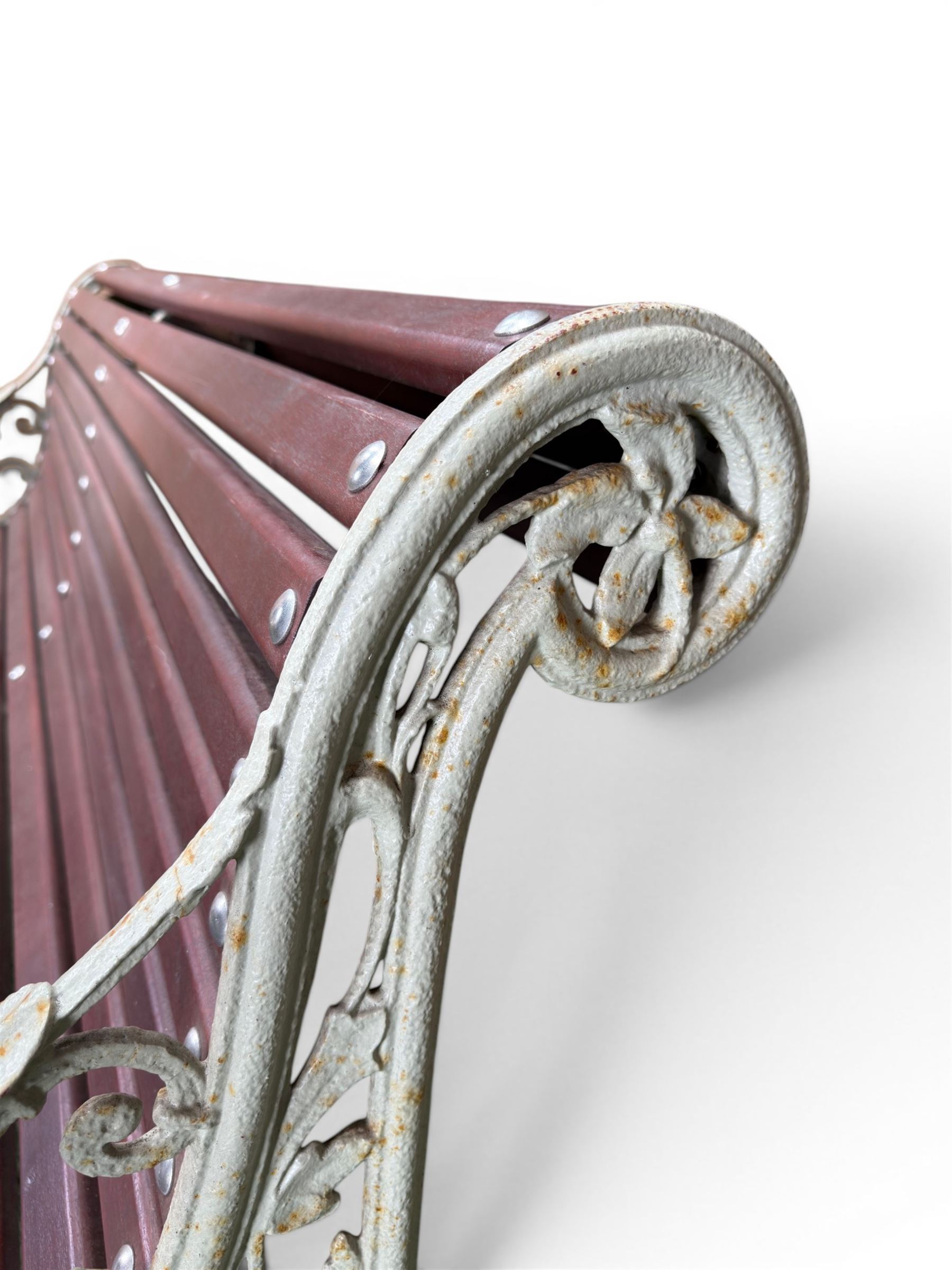 Large late Victorian cast iron garden bench, serpentine form with scroll back and seat, slatted with mahogany stained Sapele