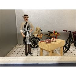 Three scratch-built wooden shop dioramas - single room Pet Shop with hinged front, fully furnished and well stocked with animals, birds and numerous accessories; and matching Garden Shop, fully furnished and well stocked with fruit, vegetables and garden accessories including lawn mower, wheelbarrows etc; each W34cm H27cm D26cm; and double fronted single room Butchers Shop with butcher at his block, partially stocked counter and two delivery cycles W57cm (3)