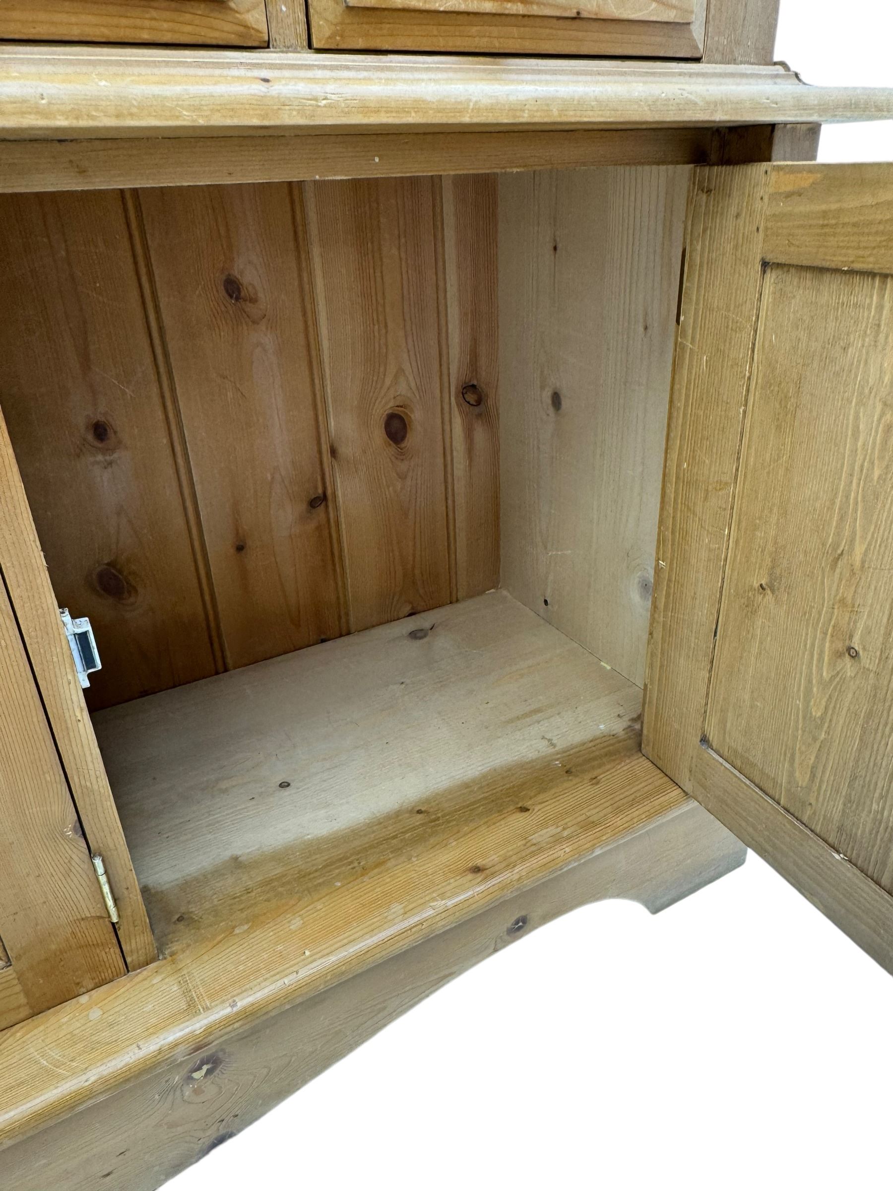 Early 20th century pine kitchen dresser, featuring a hutch with arched top over three open shelves, the base with five drawers over three cupboard doors, turned column supports flanking the doors, scalloped apron base with bracket feet