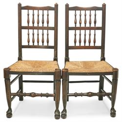 20th century set of five spindle-back dining chairs, with shaped top rails above turned spindle splats, rush seats, turned forelegs united by stretchers