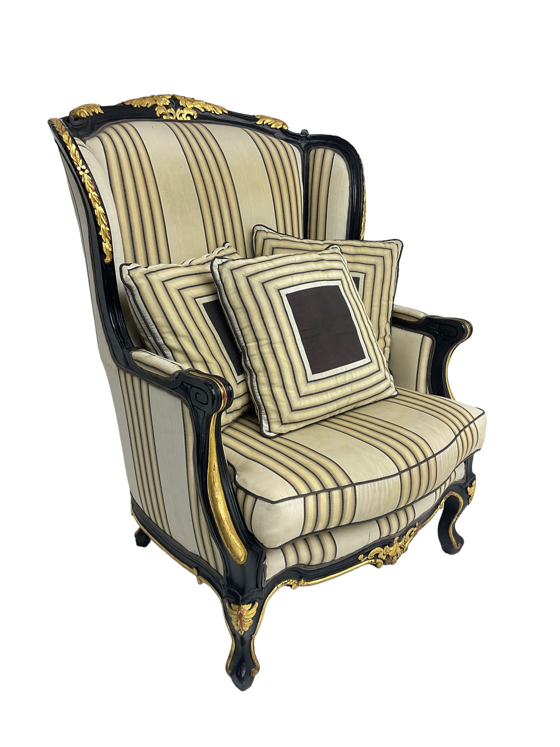 Thomas Messel - Georgian style ebonised and gilt wingback armchair, upholstered in striped fabric, on cabriole front feet