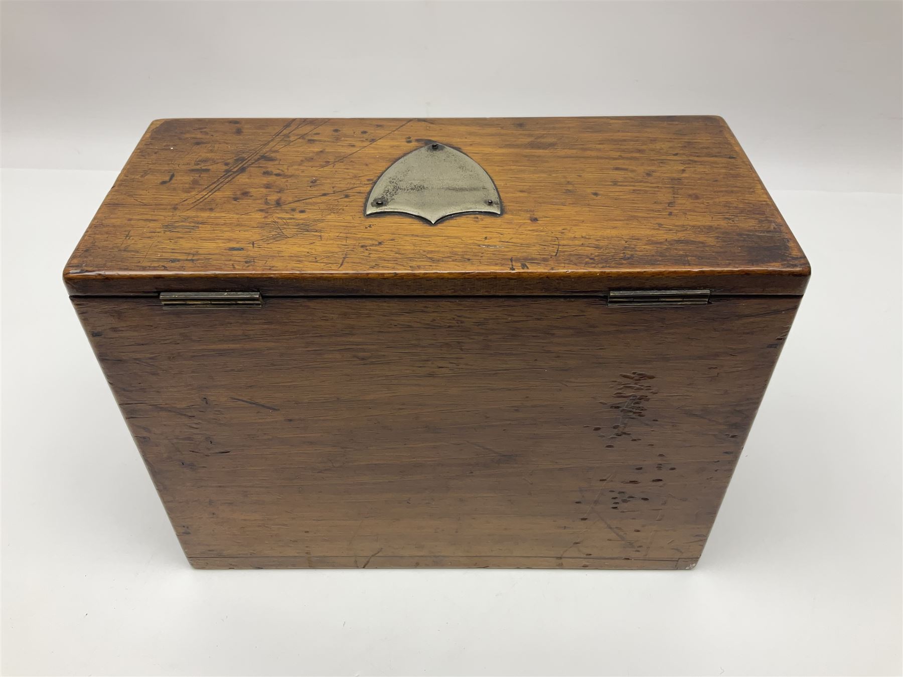 Wooden table stationery box, with drop down front and fitted interior, with metal shield plaque to the hinged lid, H18cm