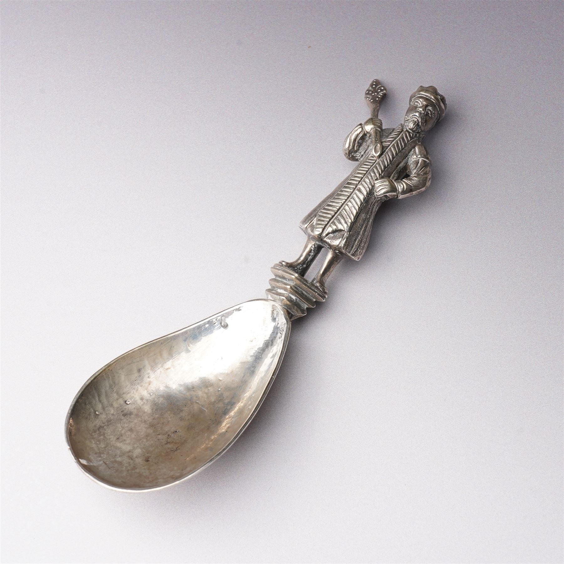 19th century Dutch silver spoon with hammered ovoid bowl, the reverse with a coat of arms, the stem formed as a standing figure after a 17th century design L13cm