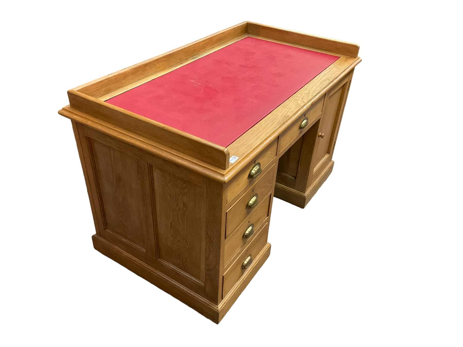 Early 20th century oak ‘Headmasters’ twin pedestal desk, three-quarter raised gallery back and inset leather writing surface, fitted with central drawer flanked by four graduating drawers and single cupboard