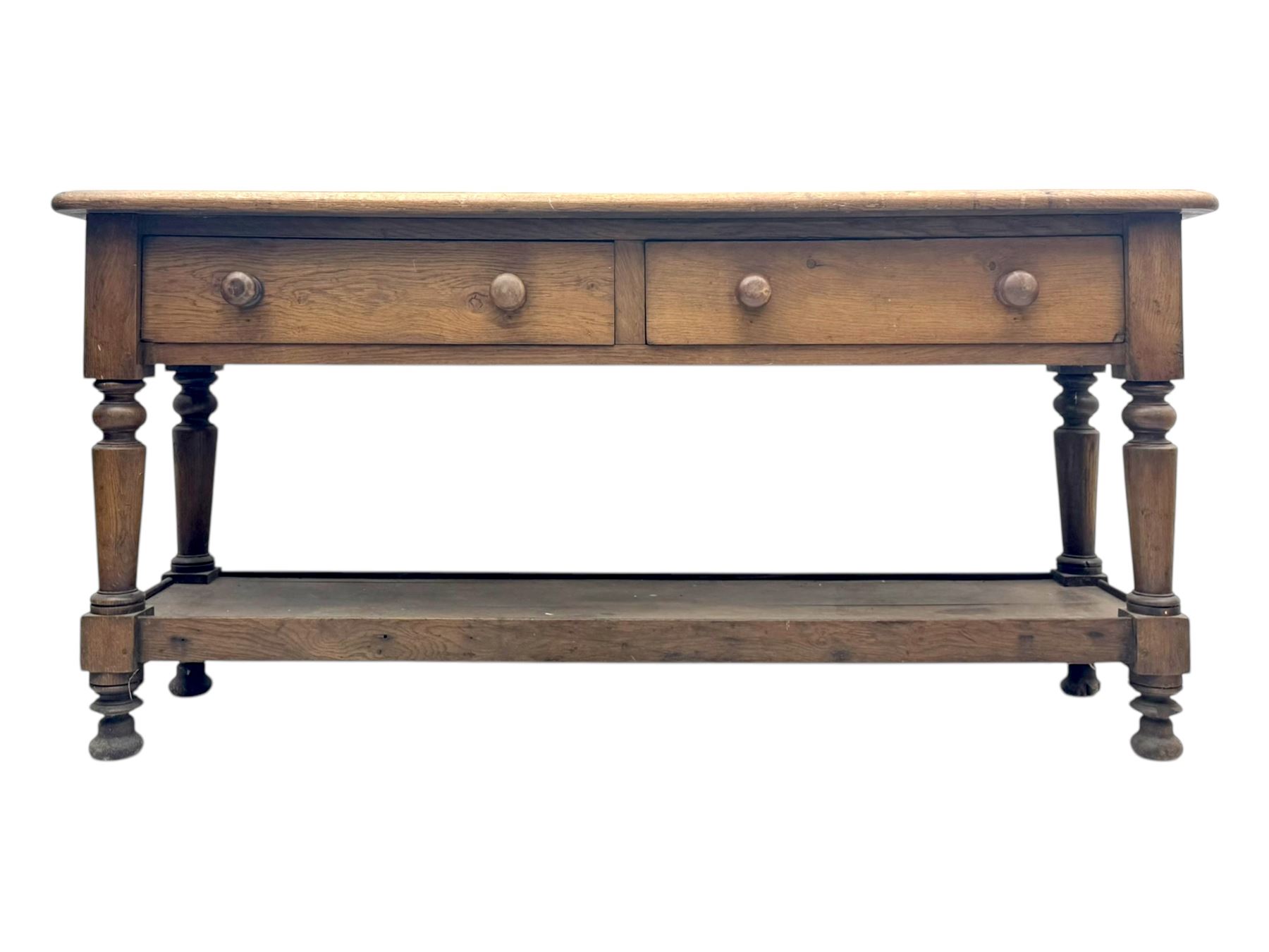 Late 19th century oak potboard dresser base, rectangular top over two frieze drawers with turned wooden handles, raised on four ring turned and tapering supports with block feet, united by a full-width lower potboard