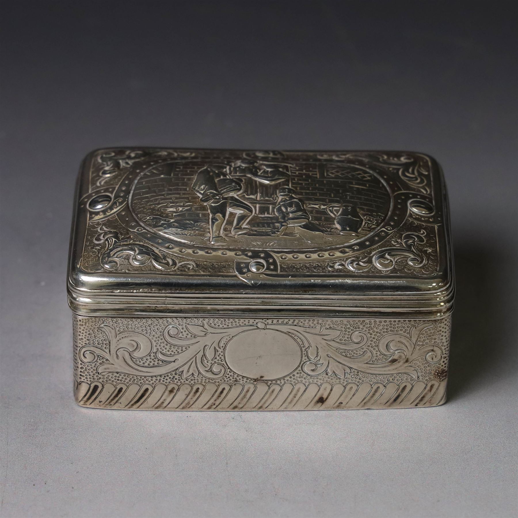 19th century Continental silver box, of rectangular form, the lift off cover with repousse figural scene, the base chased with vacant panels, acanthus scrolls and flower heads, unmarked, H4.5cm W8.5cm D5.5cm