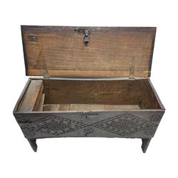 Small 17th century six plank coffer or chest, the moulded rectangular hinged top with wrought iron lock and fittings, the front and sides carved with concentric lozenges and stylised floral decoration, with vertical carved rails