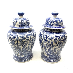 A pair of large 20th century blue and white jars and covers, each of baluster form, the domed covers with squat bun finials, each with stylised foliate decoration throughout, H50cm. 