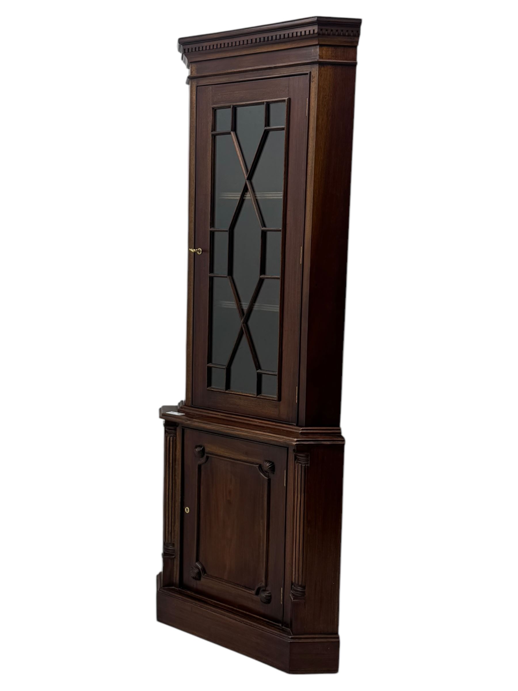 Late 20th century mahogany corner cabinet, dentil moulded cornice above a glazed door with astragal glazing enclosing two shelves, lower cupboard with fielded panel door and turned shell motif, on plinth base