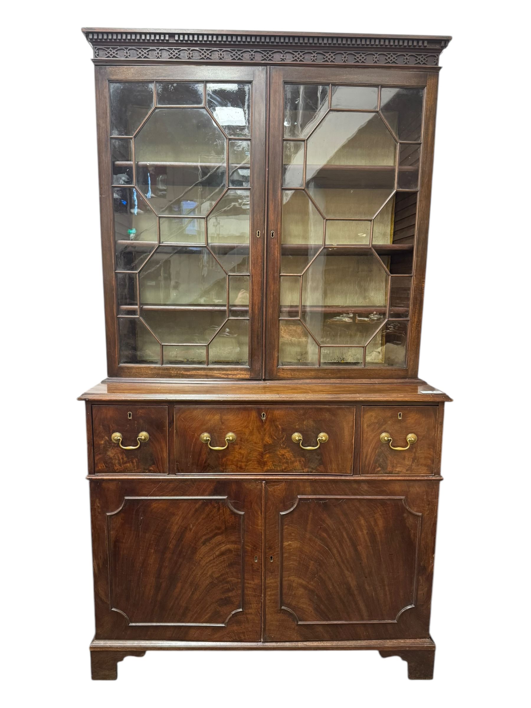 George III mahogany bookcase secretaire, dentil cornice over blind fret work frieze, enclosed by two astragal glazed doors, central secretaire drawer with fall front enclosing leather writing surface and small drawers, two flanking short drawers over double cupboard, on bracket feet