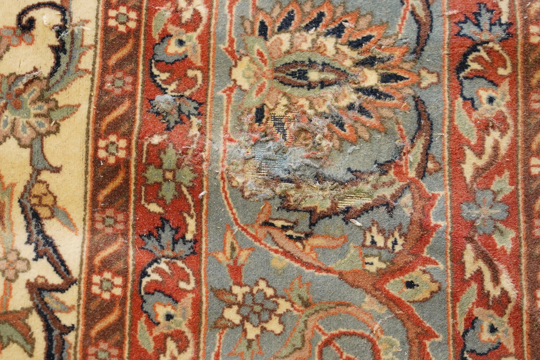 Persian Isfahan ivory and crimson ground rug, the busy field with central floral pole medallion surrounded by foliate motifs and stylised palmettes, the indigo guard line with repeating scrolling plant motifs