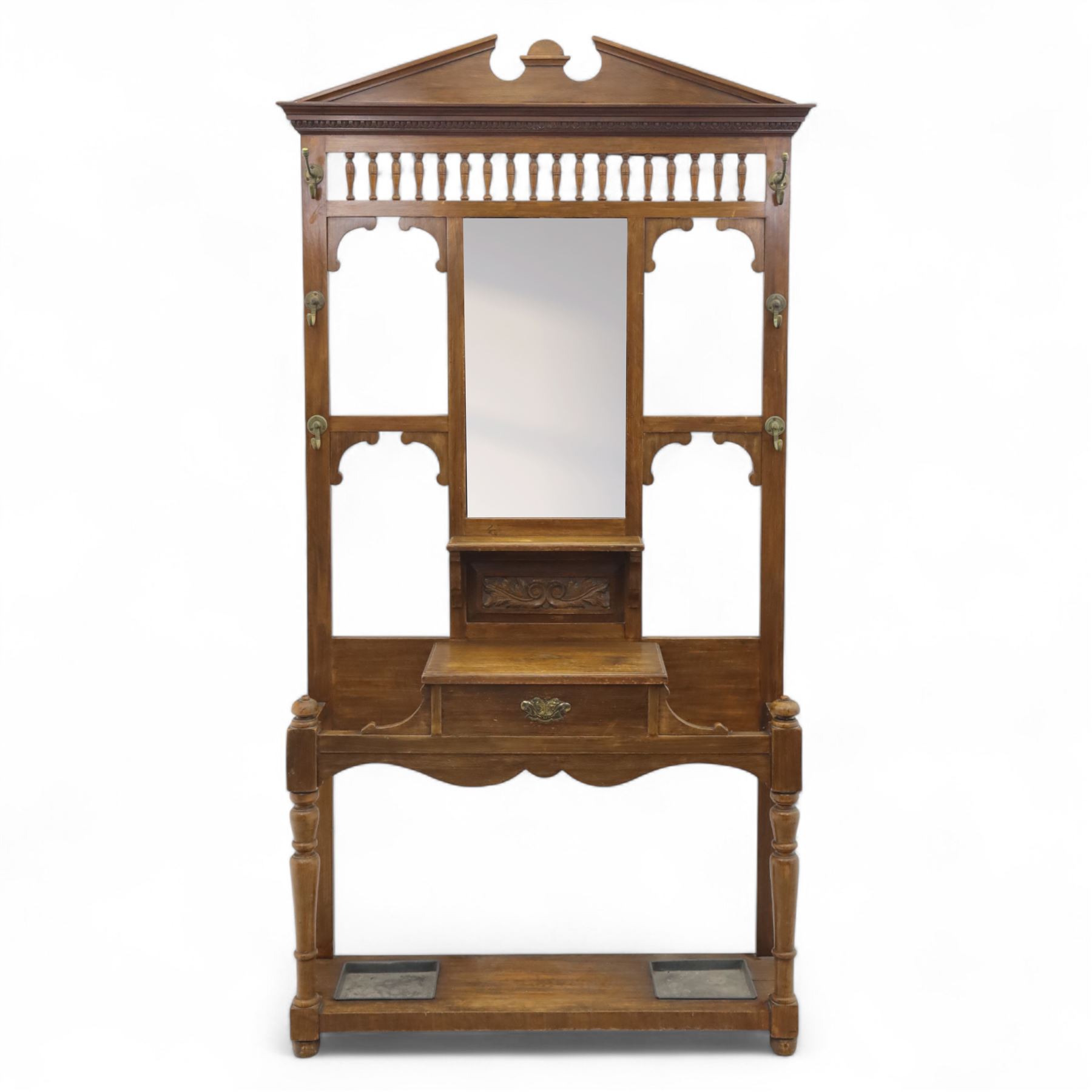 Edwardian walnut hall stand, the shaped pediment above turned spindle gallery and bevelled mirror, fitted with brass double coat hooks, single drawer with cast handle and carved frieze, flanked by turned supports, lower platform fitted with twin metal drip trays