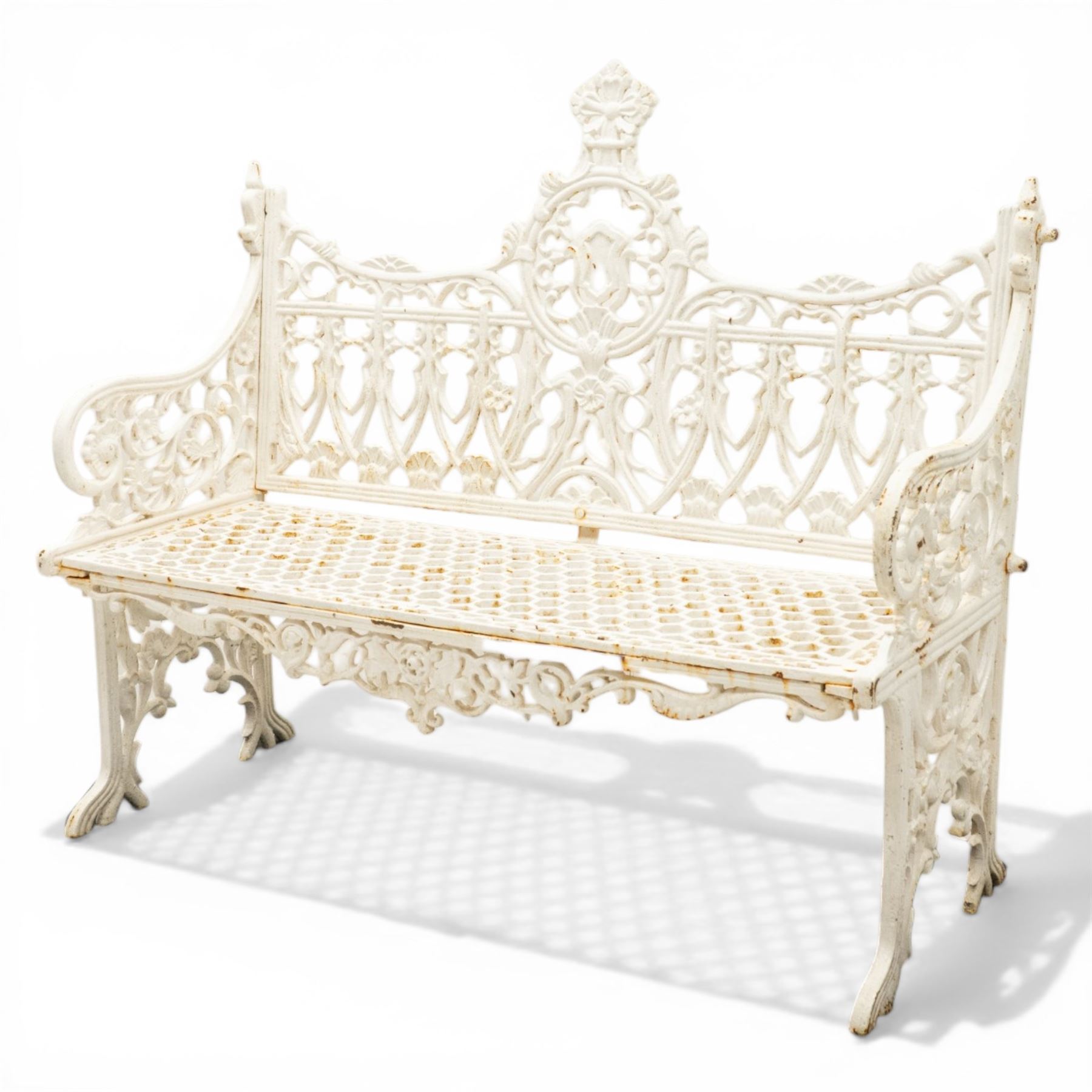 Victorian revival heavy cast iron garden bench, ornate back rest with scrolls, floral motifs and central crest, pierced lattice seat, curved arms and decorative legs, painted in antique white, in the Gothic Coalbrookdale style