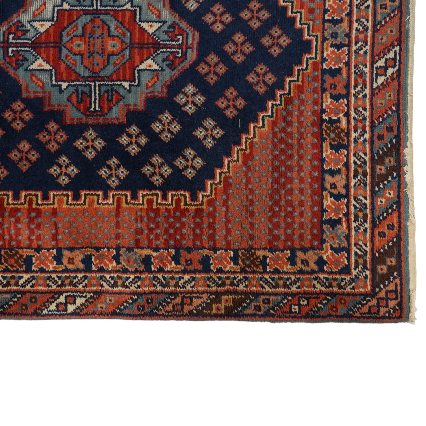 North West Persian Heriz hand-knotted rug, indigo field with three central stepped geometric medallions arranged vertically, enclosed by angular spandrels and multiple geometric borders in shades of madder red, ivory, and pale blue, with cotton fringe ends  