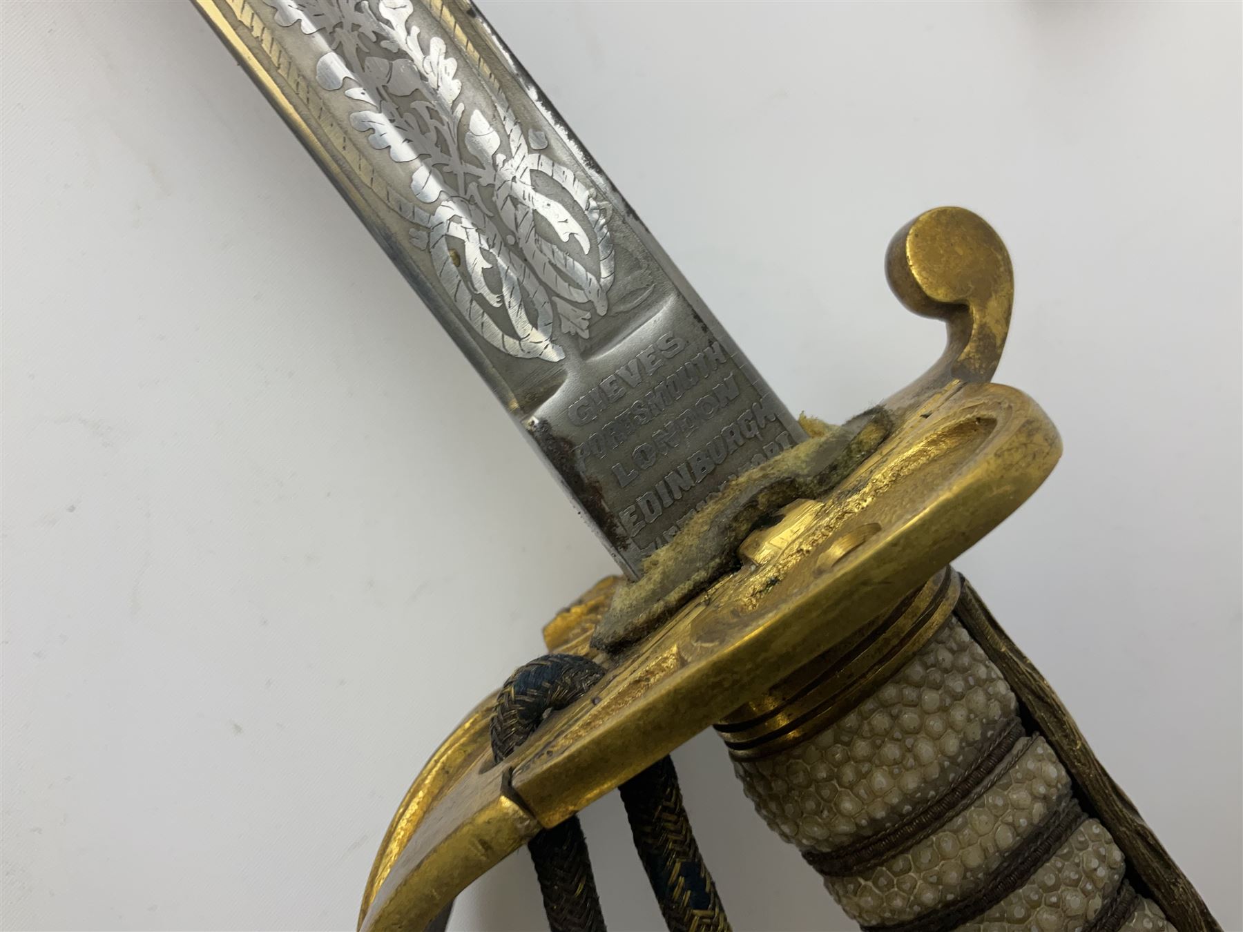 WW1 George V era 1827 Pattern Royal Naval Officer’s sword, the 80cm fullered steel blade decorated with crown, fouled anchor etc and marked Gieves Portsmouth London Edinburgh Devonport to the ricasso, gilded hilt with fouled anchor and crown, wire-bound ray skin grip, lion’s head pommel with mane backstrap, folding/locking langet and full bullion knot; in  leather scabbard having twin brass lockets with hand engraved panels and twin suspension rings L94cm overall. Provenance: By direct family descent from Brian Heathcote HMS Conqueror later Superintendant in the Liverpool Special Constabulary.