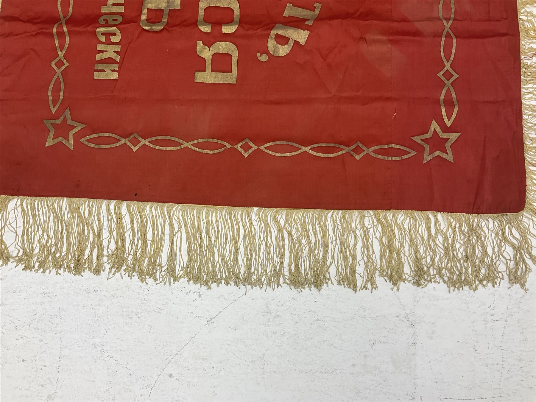 1970s Soviet banner printed in gold on a red ground, roughly translates as 'Transferable Banner - To the winner in the Socialist Competition' and 'Work Study Live by Communism' verso; wreath of wheat ears to either side; tassels on three sides 110 x 155cm