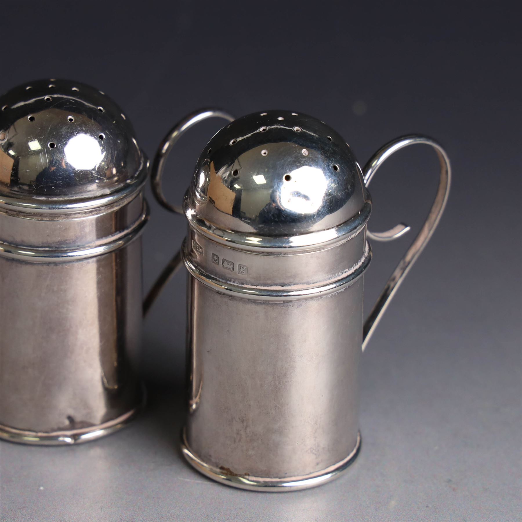 Pair of Edwardian silver muffineers, of cylindrical form with C scroll handles and removable pierced covers, hallmarked G E Walton & Co Ltd, Birmingham 1906, H6cm