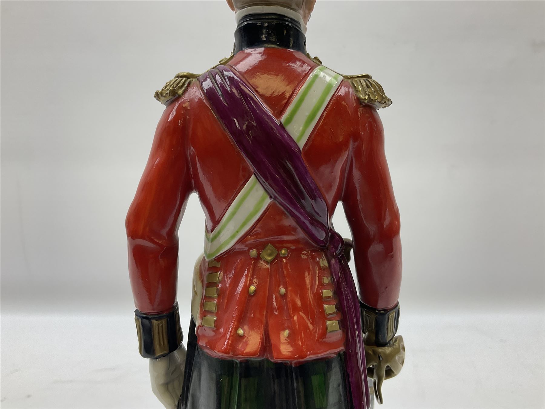 Sitzendorf figure, The Black Watch officer, c1815 standing to attention in full dress with sword, blue factory marks beneath, H28cm