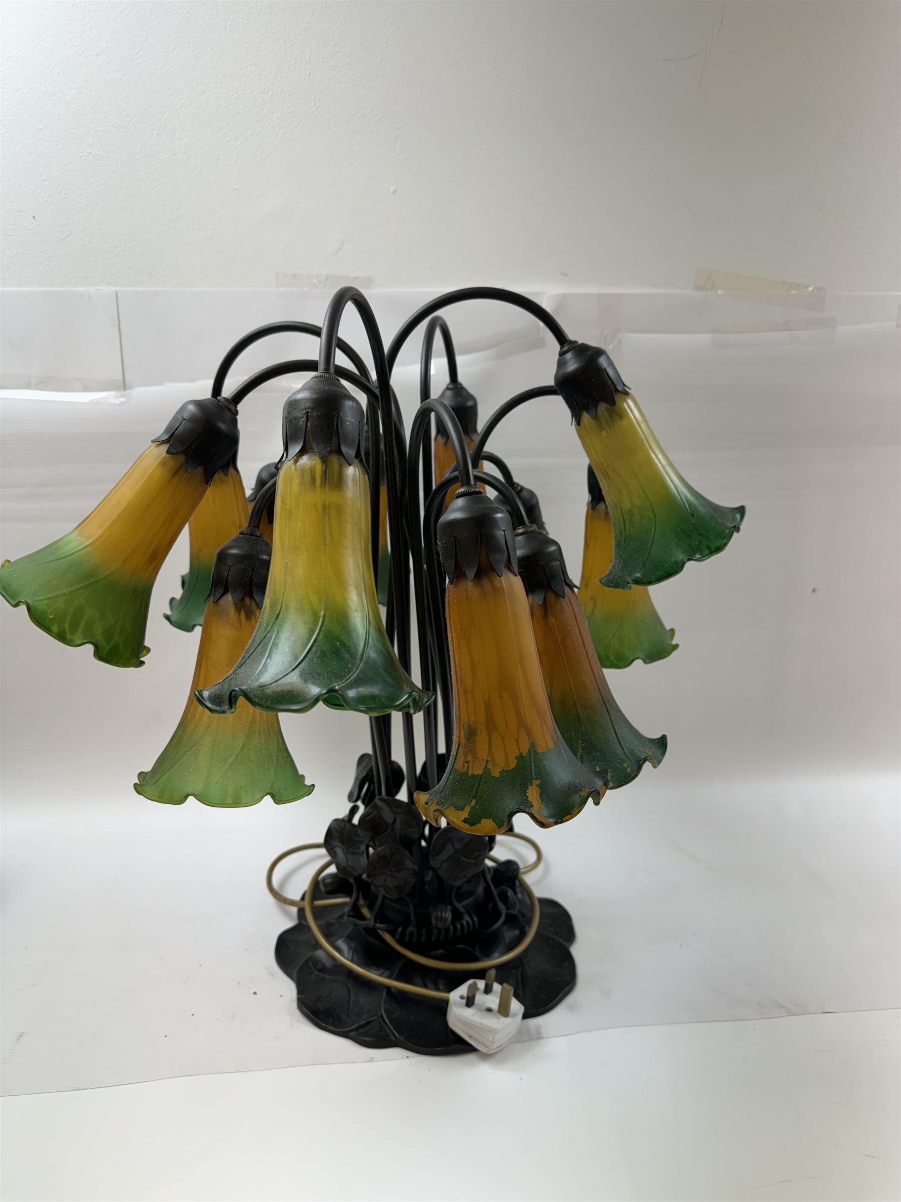 Art Nouveau Tiffany style table lamp, the bronzed base modelled as lily pads leading to tendrils and twelve branches supporting green and yellow glass lily flower shades, H53cm