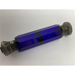 Late Victorian silver mounted ruby glass cylindrical scent bottle, with interior glass stopper, Birmingham 1900, makers mark worn, H8cm, together with a Victorian double ended cut blue glass perfume bottle mounted with white metal screw and flip caps decorated with foliate repousse detailing, H13.5cm