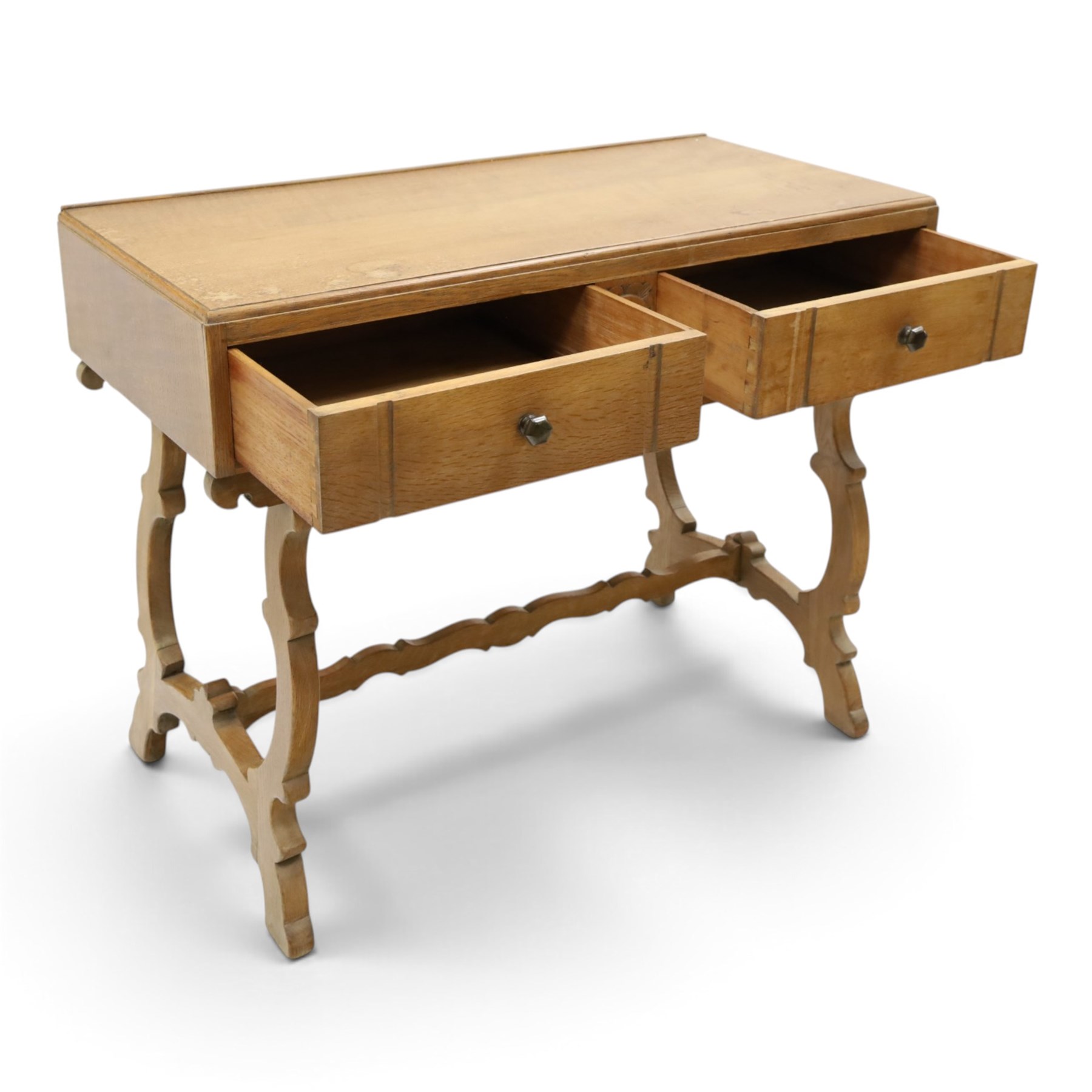 Leemings of Halifax (est. 1872) - Arts & Crafts oak side table, rectangular caddy top with raised moulded back, the frieze carved with central Yorkshire rose motif flanked by two drawers, raised on twin stylised lyre end supports formed of C-scrolls, united by shaped stretcher
