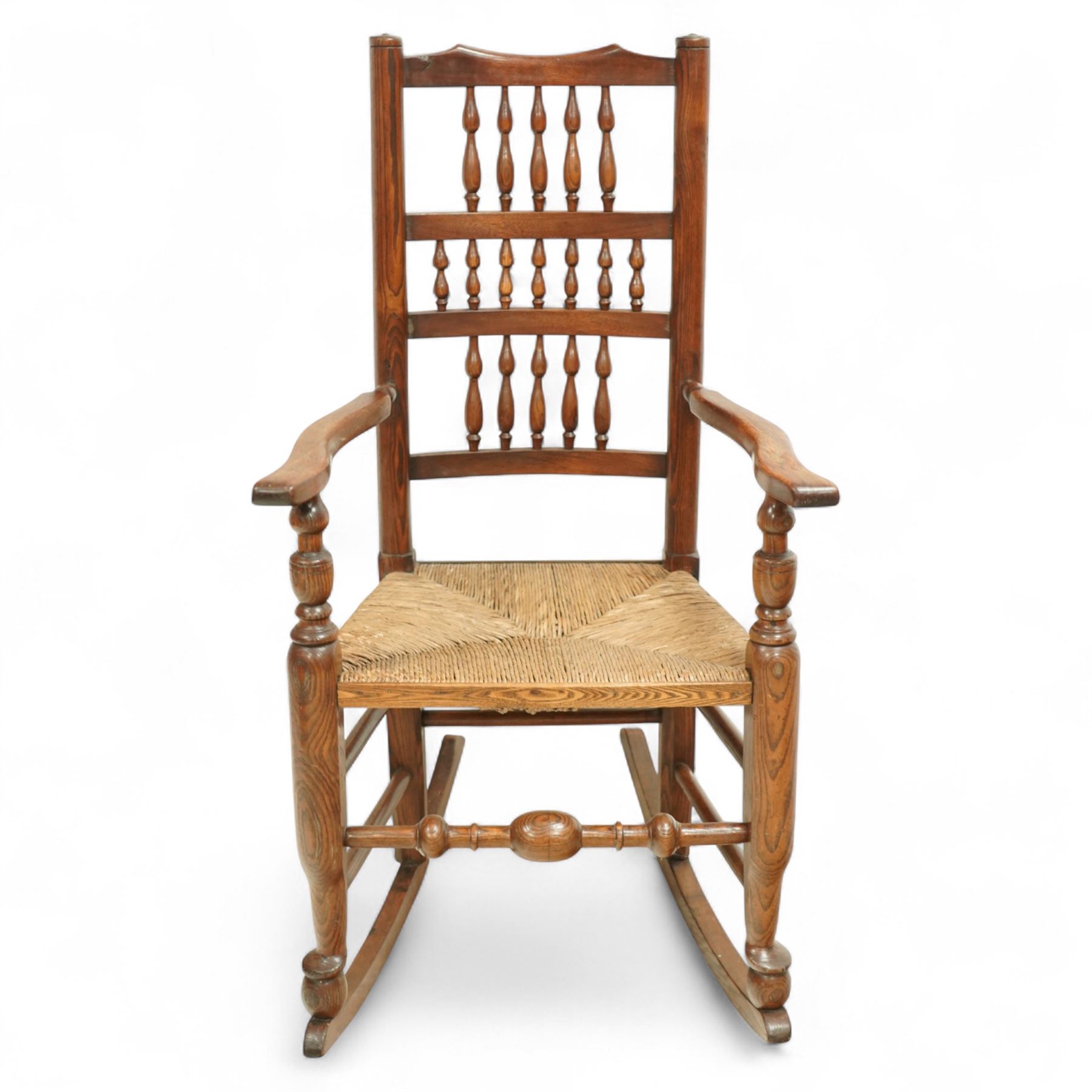 Lancashire elm rocking chair, shaped cresting rail over triple row bobbin turned spindles, woven rush seat, on curved rockers