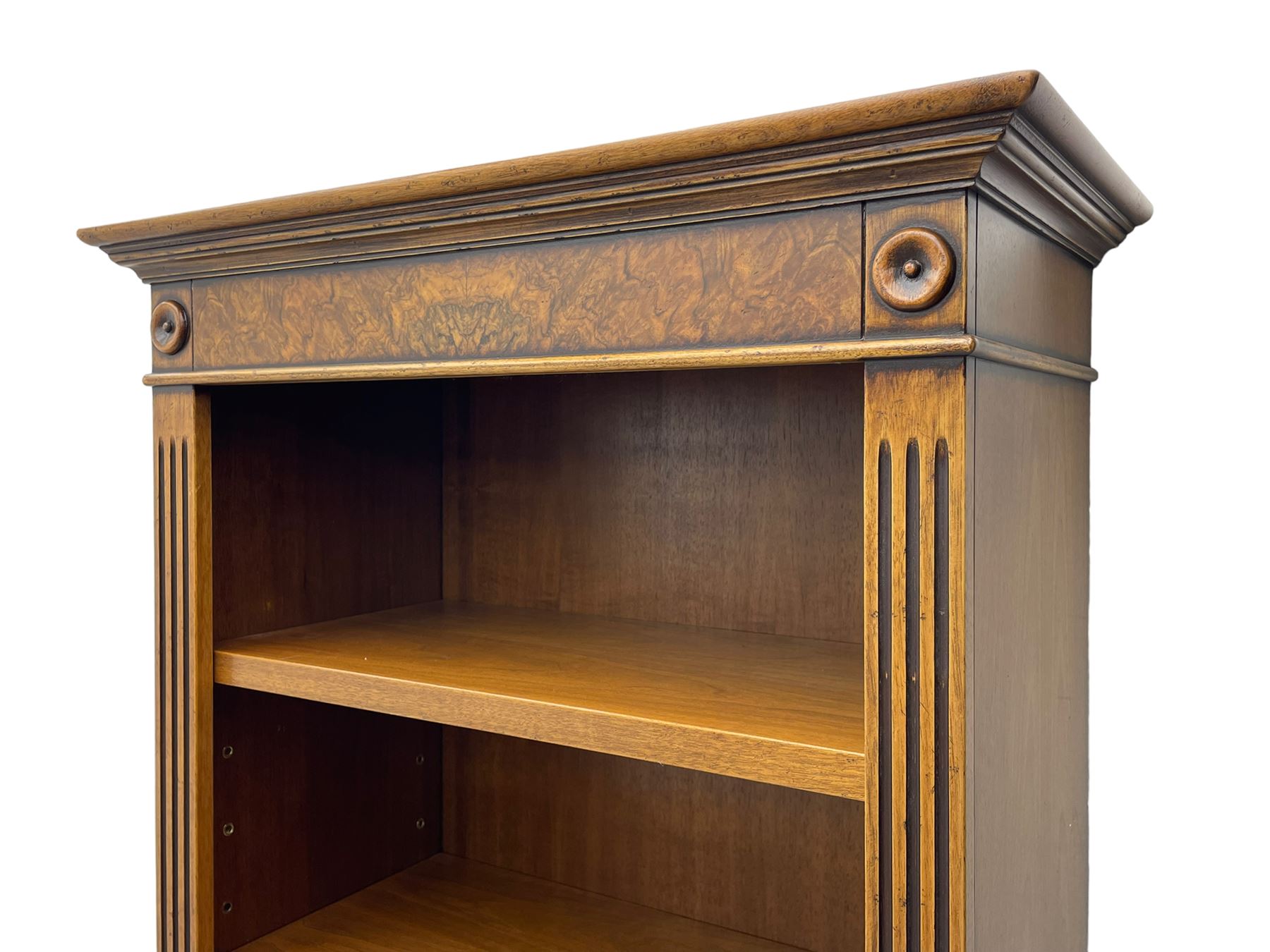 Georgian design walnut open bookcase, projecting cornice over figured banded frieze flanked by roundels, fitted with six adjustable shelves with flanking fluted uprights, on skirted base