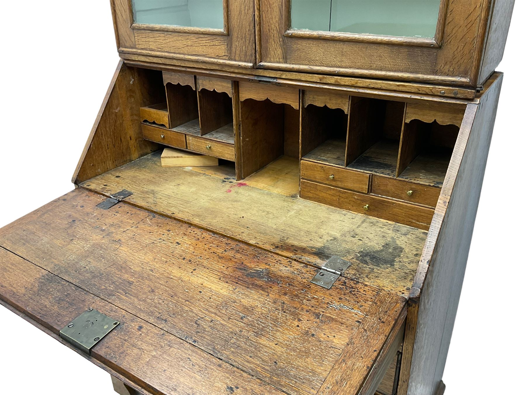 George III oak bookcase on bureau, the double arched top enclosed by two shaped glazed doors, fall-front concealing fitted interior, over four graduating cock-beaded drawers, on bracket feet
