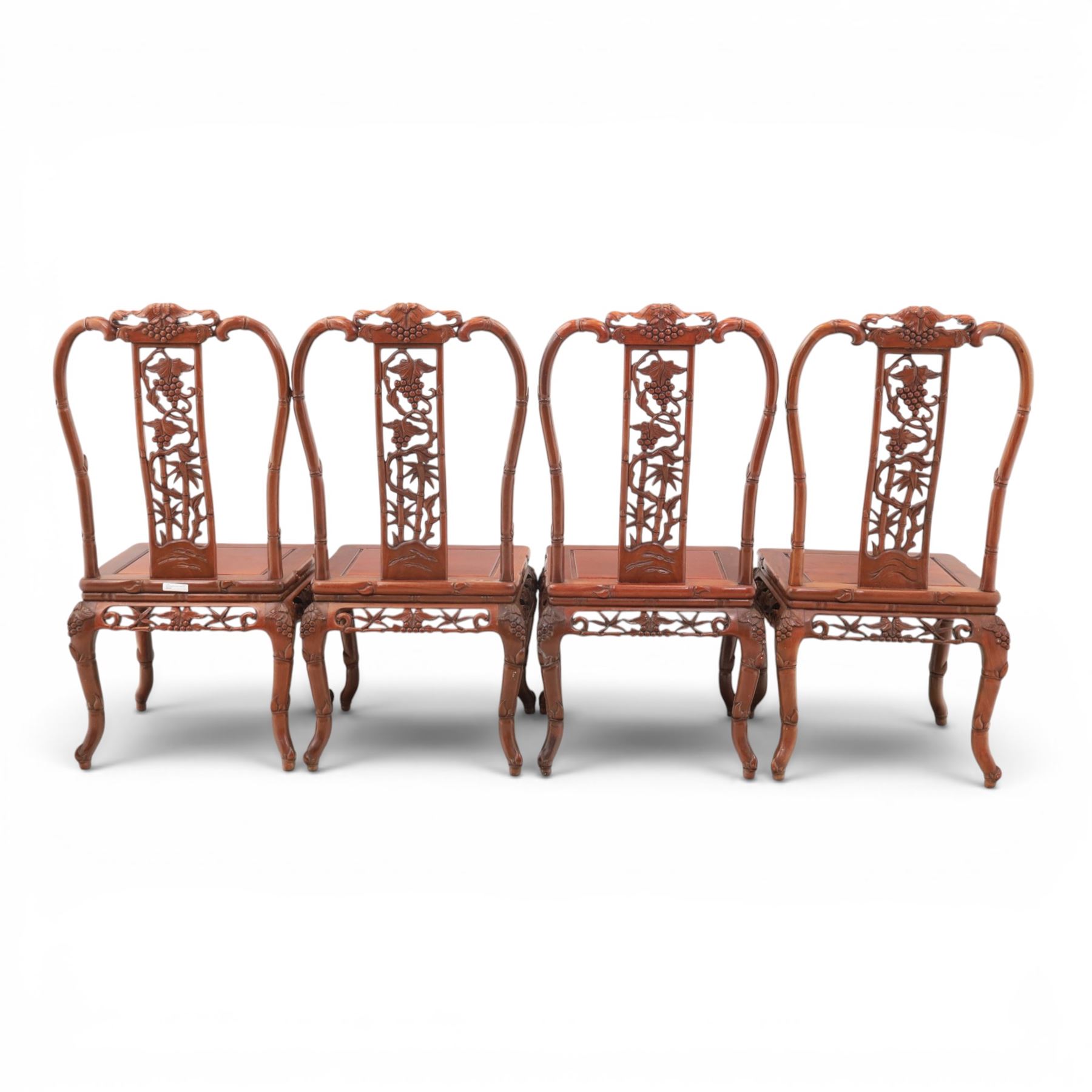 20th century Chinese ornately hardwood dining table and chairs, circular table with 'Lazy Susan' top with pierced carved frieze, raised on a quadriform base with carved foliate detail, the chairs en suite with carved pierced detailing  