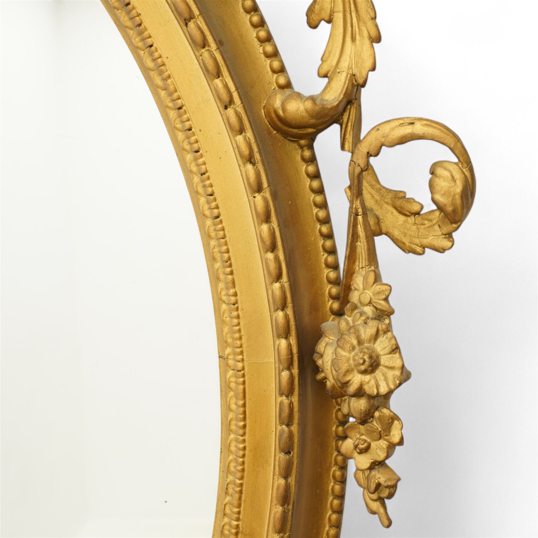 Late 19th century Louis XVI style giltwood and gesso girandole oval wall mirror, the oval frame surmounted with stylized urn finial and ribbon-tied garlands, laurel swags and rosettes, egg and dart decorated inner moulding and linked acorn outer moulding, flanked by intertwined foliate decorated candle branches 
