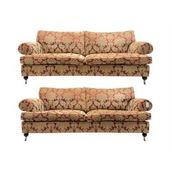 Duresta - pair of Grande three-seat sofas, traditional shaped with rolled arms and upholstered loose cushions, in red ground fabric with raised gold foliate pattern, on turned feet with brass castors 